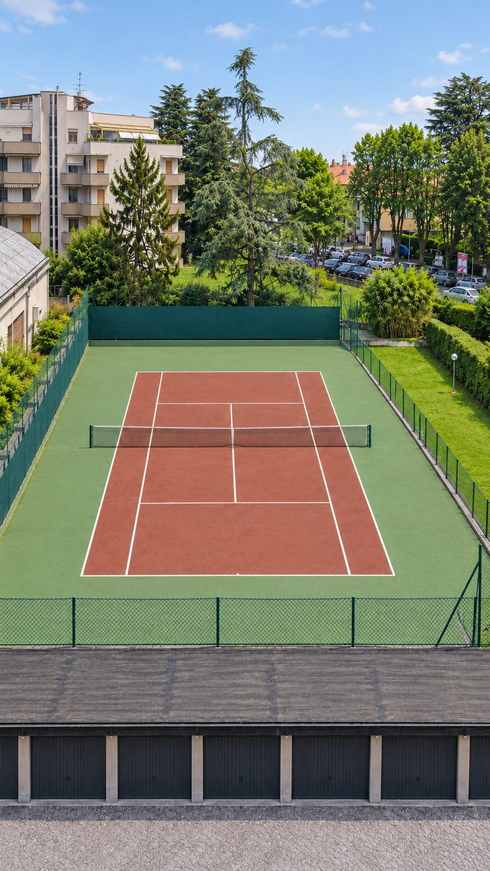 Il campo da tennis condominiale visto dall'alto, circondato dal verde